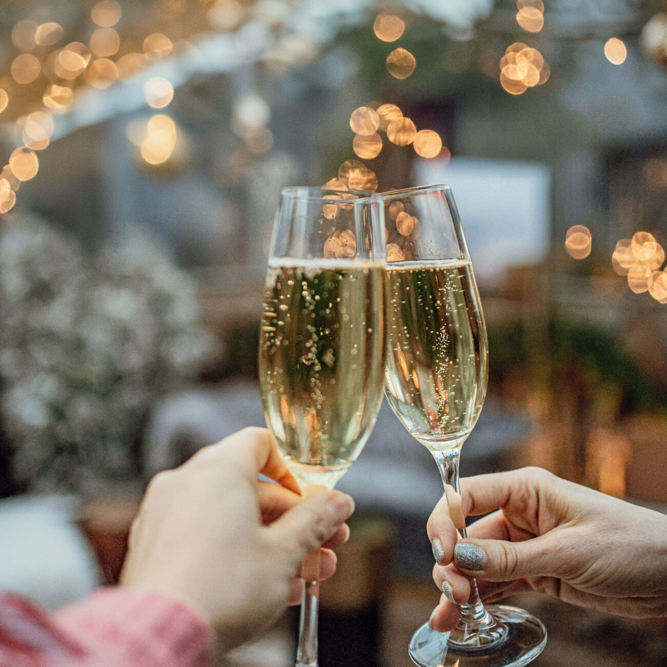 Champagne glasses toast under string lights